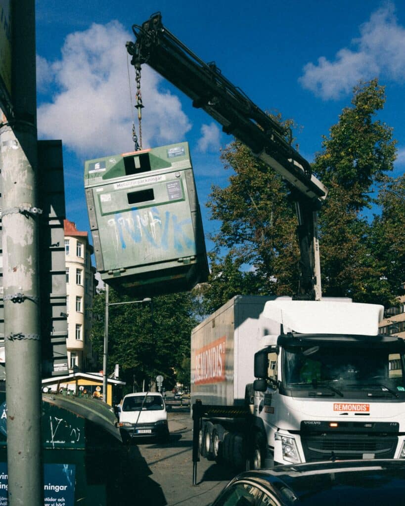Roll-off dumpster being lifted onto a truck on a city street